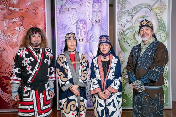 Four Ainu artists stand in a row wearing traditional cultural garb